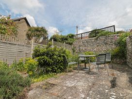 A patio area with a table and four chairs surrounded by stone walls and fences at Lavender Cottage in Lyme Regis