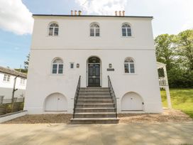 A white two-story house with arched windows and a central black door accessed by stairs at The Garden Flat in Charmouth