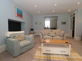 A living room with a blue armchair and a beige sofa around a wooden coffee table with coasters at The Garden Flat in Charmouth