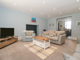 A living room with sofas a coffee table a TV and an open doorway to a kitchen at The Garden Flat in Charmouth