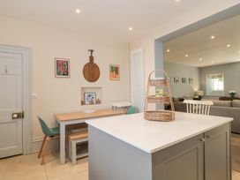 A kitchen with a dining table and chairs and an island with a basket at The Garden Flat in Charmouth