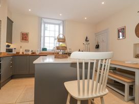 A kitchen with grey cabinets a white chair and wooden dining table at The Garden Flat in Charmouth