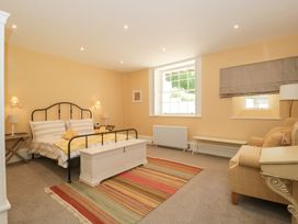 A bedroom with a double bed a striped rug and a sofa at The Garden Flat in Charmouth