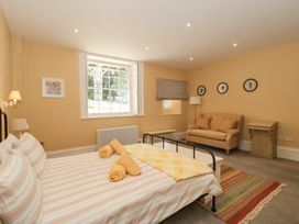 A bedroom with a bed, rolled towels, a sofa, framed wall art, a rug, and a window at The Garden Flat in Charmouth