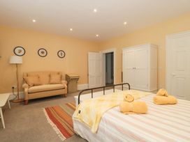 A bedroom with a bed, sofa, floor lamp, wardrobe, and framed pictures on the wall at The Garden Flat in Charmouth