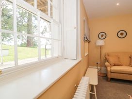 A room with a window showing grass and trees a radiator a bench a floor lamp and a sofa with cushions at The Garden Flat in Charmouth