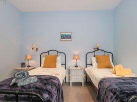 A bedroom with two single beds with pillows and blankets and bedside tables with lamps at The Garden Flat in Charmouth