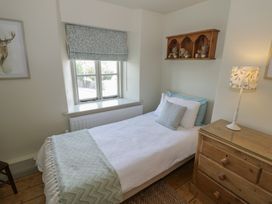 A bedroom with a bed, dresser, lamp, and window at Robins Nest in Bourton-On-The-Water