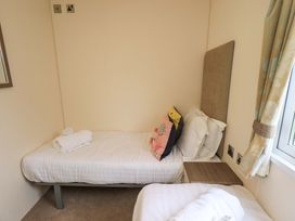A bedroom with two beds and a bedside table at 41, Grandma's Cottage South Lakeland Leisure Village near Carnforth