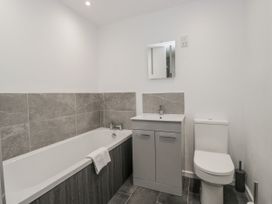 A bathroom with a bathtub, toilet, sink and mirror at Clarence House in Dalton-In-Furness