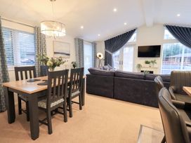 A living room with a sofa and dining area at Unique Luxury Lodge, 1 Langdale, White Cross Bay near Windermere