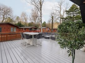 An outdoor deck with furniture and trees at Unique Luxury Lodge, 1 Langdale, White Cross Bay near Windermere