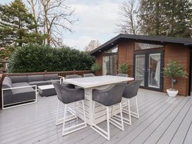An outdoor deck with seating and a dining table at Unique Luxury Lodge, 1 Langdale, White Cross Bay near Windermere