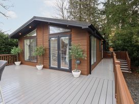 A timber lodge with a wooden deck and potted plants at Unique Luxury Lodge, 1 Langdale, White Cross Bay near Windermere
