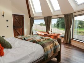A bedroom with a bed and large windows at Ty Crwn in Lampeter