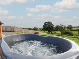 A hot tub with water and trees in the background at Ty Crwn in Lampeter