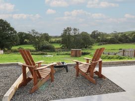 A seating area with chairs and a fire pit overlooking a field at Ty Crwn in Lampeter