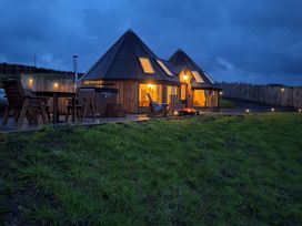 An outdoor view of a wooden cabin with chairs and a table at Ty Crwn - The Roundhouse near Lampeter