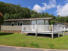 A cabin with a deck and garden at Serenity in Kilgetty