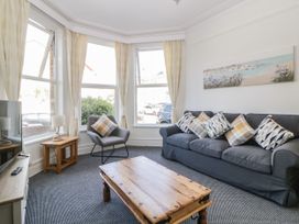 A living room with a grey sofa and patterned cushions a grey armchair and a wooden coffee table at 5 Stafford Road in Paignton