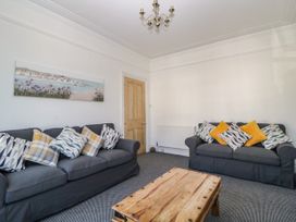 A living room with two dark gray sofas with patterned and yellow cushions and a wooden coffee table at 5 Stafford Road Paignton