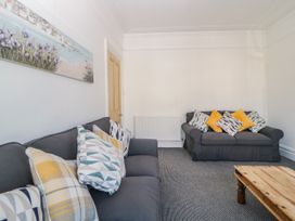 A living room with two gray sofas with patterned cushions and a wooden coffee table at 5 Stafford Road in Paignton
