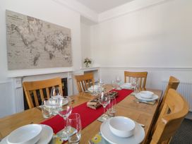 A dining room with a wooden table set with white bowls wine glasses and water glasses a red table runner and a world map on the wall at 5 Stafford Road in Paignton