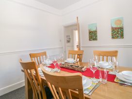 A dining room with a wooden table and six chairs set with plates glasses and bowls at 5 Stafford Road in Paignton