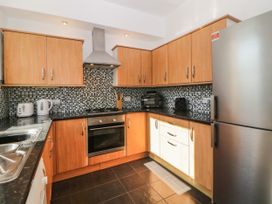 A kitchen with wooden cabinets black countertops tiled backsplash and stainless steel appliances at 5 Stafford Road in Paignton