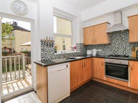 A kitchen with wooden cabinets black countertops mosaic tile backsplash dishwasher and door leading outside at 5 Stafford Road in Paignton