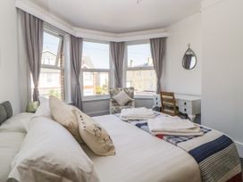 A bedroom with a bed pillows folded towels armchair desk chair window with curtains and a wall mirror at 5 Stafford Road Paignton