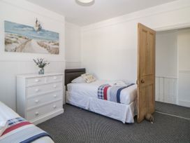 A bedroom with two single beds a white chest of drawers and a wooden door at 5 Stafford Road Paignton