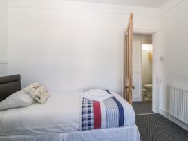 A bedroom with a single bed with a pillow and folded towels next to an open door leading to a bathroom at 5 Stafford Road in Paignton