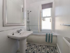 A bathroom with a pedestal sink mirror bathtub shower window and patterned floor tiles at 5 Stafford Road Paignton