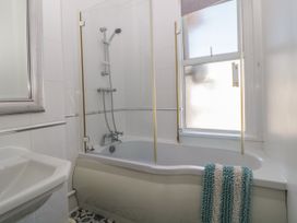 A bathroom with a bathtub and shower combination a sink a window and a striped towel at 5 Stafford Road in Paignton