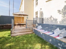 A garden with wooden deck seating and a picnic table under an umbrella at 5 Stafford Road in Paignton