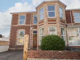 A brick house with bay windows a wooden door and a green bush behind a low brick wall at 5 Stafford Road in Paignton