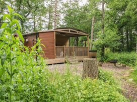 A cabin with a deck and fire pit surrounded by trees at The Leveret in Eppleby