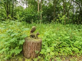 A wooden sculpture of an animal on a tree stump in a forest clearing