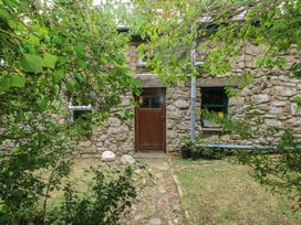 A stone wall with a wooden door and plants at Penfeidr Newydd in Carningli Common, Newport, Pembrokeshire