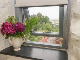 A window with a flower arrangement and teapot at Penfeidr Newydd, Carningli Common, Newport, Pembrokeshire