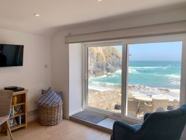 A living room with a window overlooking rocky coastline at Beach Cottage in Cadgwith