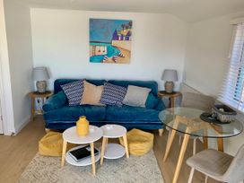 A living room with a sofa, coffee table, and dining table at Beach Cottage in Cadgwith