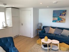 A living room with a sofa, coffee table and kitchen at Beach Cottage in Cadgwith