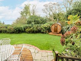 A garden with seating, a barrel sauna, and grass at Glenside House in Carbis Bay