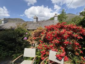 A garden with flowers and chairs at Glyn Awel in Nant Gwynant near Beddgelert