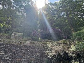 A garden with sunlight filtering through trees at Glyn Awel Nant Gwynant near Beddgelert