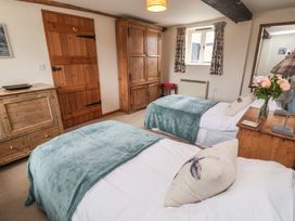 A bedroom with twin beds and a wooden dresser at The Cow Shed in Chediston near Halesworth