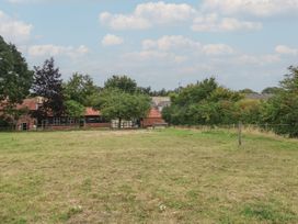 An outdoor scene of a field with trees and farm buildings at The Cow Shed in Chediston near Halesworth