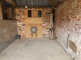 A games room with a dartboard and chair at The Cow Shed in Chediston near Halesworth